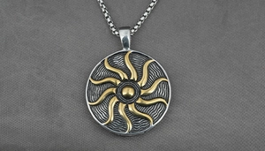 Detailed macro view of silver titanium steel sun pendant necklace with golden flame motif