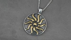 Detailed macro view of the silver sun pendant with golden embossed flame pattern on box chain