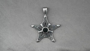 Détail macro du pendentif étoile gothique avec pierre noire et motifs de vignes