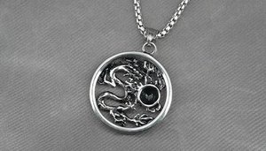 Détail macro du pendentif dragon vintage avec pierre noire sur chaîne en acier inoxydable