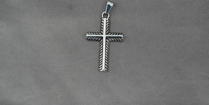 Macro shot of silver vintage cross pendant with detailed cable texture and polished accents