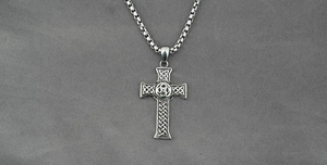 Macro detail of Celtic knot cross pendant in titanium steel with polished box chain link