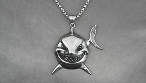 Detailed close-up of a silver shark pendant featuring sharp teeth and fine steel box chain