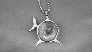 Detailed view of a silver shark pendant featuring unique fingerprint texture on box chain