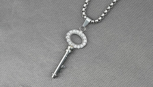 Dettaglio macro della collana con ciondolo a chiave in argento e diamanti su catena veneziana