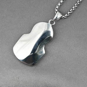 Polished silver stainless steel necklace with organic wave pendant on grey fabric