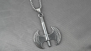Close-up of vintage stainless steel double-headed axe pendant with detailed engraving