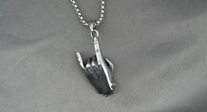 Détail macro du pendentif main rock en acier titane sur une chaîne à mailles carrées
