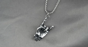 Gros plan d'un pendentif tête de mort geste rock et d'un collier en acier inoxydable
