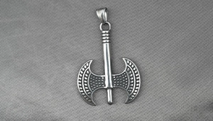 Close-up of double-sided battle axe pendant in vintage steel with intricate engravings