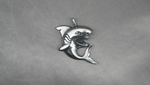 Close-up of a vintage silver shark pendant with detailed oxidized muscle lines and teeth