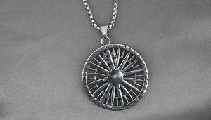 Macro detail of silver compass pendant with numerical scales on gray silk fabric