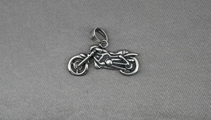 Détail d'un pendentif moto vintage avec finition argentée rétro et textures mécaniques