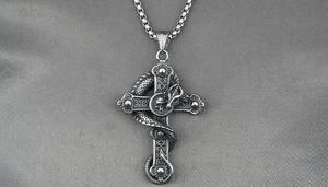 Macro shot of vintage steel gothic pendant featuring a flying dragon, cross and skull details