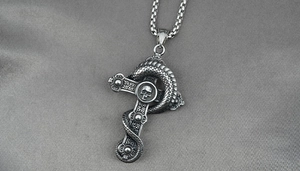 Close-up of gothic stainless steel cross necklace with skull and snake detailing