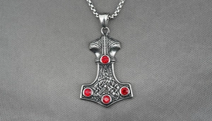 Detailed view of silver Viking Mjolnir pendant with Celtic knots and red crystals