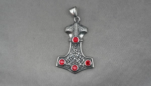Detailed view of silver Viking Mjolnir pendant with red gems and Celtic engraving