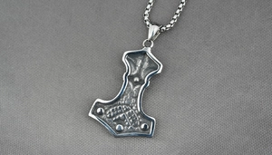 Detail of vintage silver Viking Mjolnir pendant with intricate embossed texture and box chain