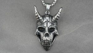 Detail of gothic devil skull pendant with cross and vintage blackened steel texture