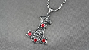 Detailed close-up of Mjölnir pendant necklace with red crystals and Viking patterns