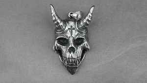 Detailed close-up of gothic silver skull pendant with horns and cross on gray fabric