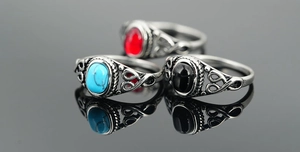 Close-up of vintage titanium steel rings with blue, black, and red gemstone inlays