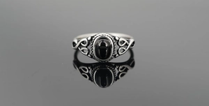 Macro shot of vintage titanium steel ring with black oval stone and intricate tribal patterns