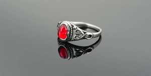 Macro shot of vintage silver ring with red oval stone and ornate scrollwork details