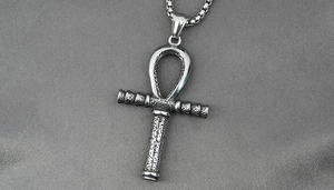 Macro shot of stainless steel Ankh cross pendant with vintage relief on grey fabric