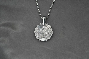 Dettaglio del ciondolo mandala in argento con una trama a nido d'ape sul lato posteriore