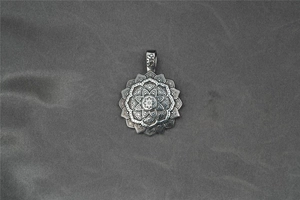 Dettaglio del ciondolo mandala vintage in argento con simbolo sacro Om inciso sul gancio