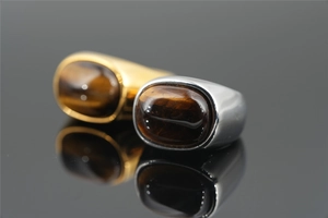 Macro detail of gold and silver tiger eye stone rings on a black reflective surface