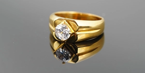 Gros plan d'une bague pour homme en titane doré avec un zircon serti au centre
