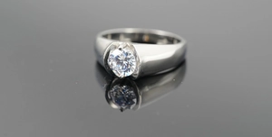 Macro view of men's wide titanium steel ring with a round-cut diamond on mirror background