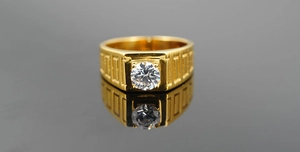 Gros plan sur une bague d'homme dorée large avec zircon et texture géométrique