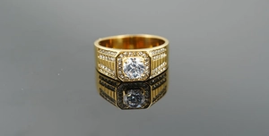 Gros plan d'une bague pour homme en or avec une large pierre centrale et des détails pavés