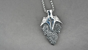 Close-up of stainless steel leaf pendant with black cross and feather texture detail