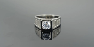 Détail d'une bague large en titane avec motifs rectangulaires et pierre centrale ronde