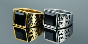 Macro view of gold and silver signet rings with black square gemstones and cross engraving