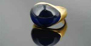 Vista macro di un anello vintage in titanio dorato con una grande gemma blu ovale