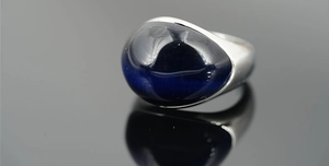 Macro di una pietra occhio di tigre blu ovale su un anello largo in acciaio lucido argento