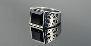 Macro view of men's signet ring featuring a black square gemstone and hollow cross patterns