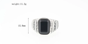 Dettaglio anello vintage da uomo in acciaio con pietra nera e motivo decorativo greco