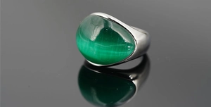 Macro di un anello in titanio argento con una grande pietra verde occhio di gatto ovale