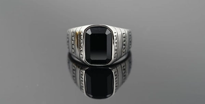 Dettaglio anello vintage da uomo in acciaio con pietra nera taglio smeraldo e incisione