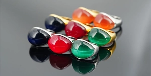 Vista macro di anelli con gemme cabochon multicolore e fasce in oro e argento riflettenti