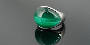 Dettaglio macro anello in titanio argento con pietra preziosa occhio di gatto verde