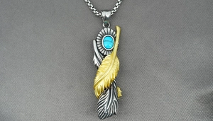 Macro shot of vintage silver and gold feather pendant necklace with turquoise stone detail