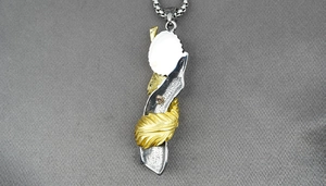 Detail of silver and gold feather pendant on a stainless steel chain for men