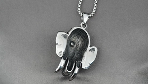 Vue macro d'un pendentif tête d'éléphant en acier inoxydable avec détails noirs vintage